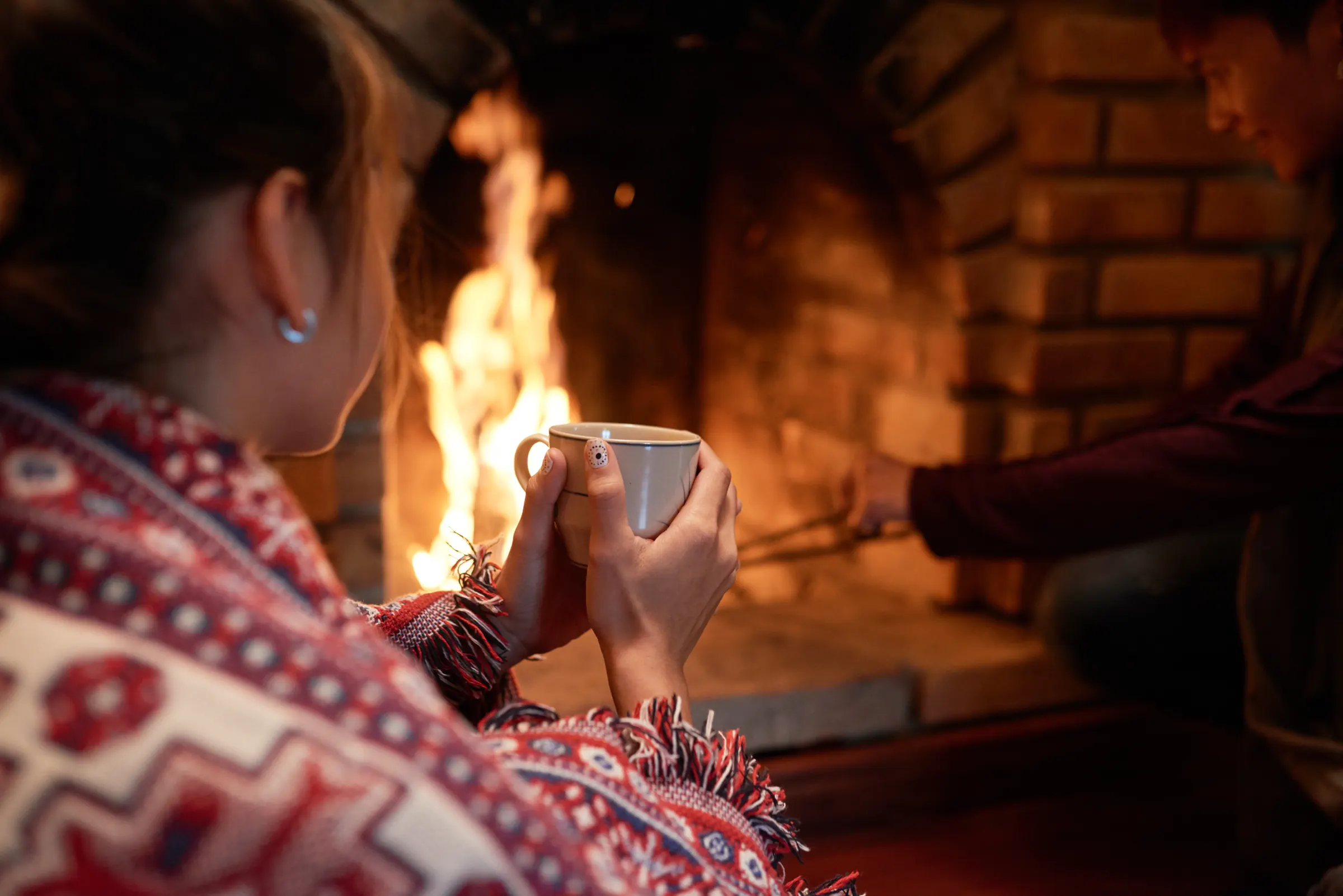 Couple qui se réchauffe près d'un feu de foyer avec une tasse de thé